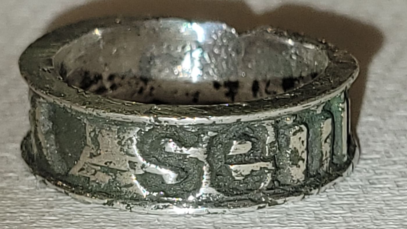 Finished cast metal ring with raised lettering